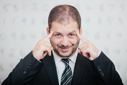 Australian Memory Champion Tansel Ali in suit pointing to his temples/brain
